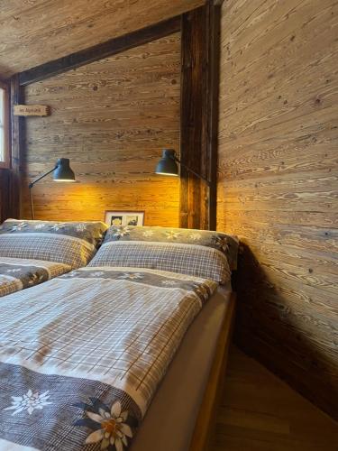 two beds in a room with wooden walls at Restaurant Hotel Schermtanne in Adelboden