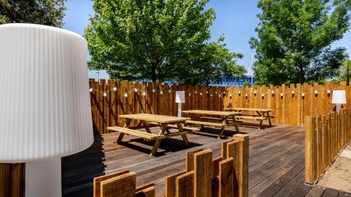 a wooden deck with picnic tables and a fence at Akena Nantes Atlantis Zénith in Saint-Herblain