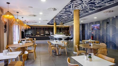 a restaurant with tables and chairs and a bar at Akena Nantes Atlantis Zénith in Saint-Herblain