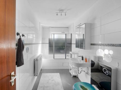 ein weißes Badezimmer mit einem Waschbecken und einem Spiegel in der Unterkunft Work & Stay in Adelheitsdorf in Adelheidsdorf
