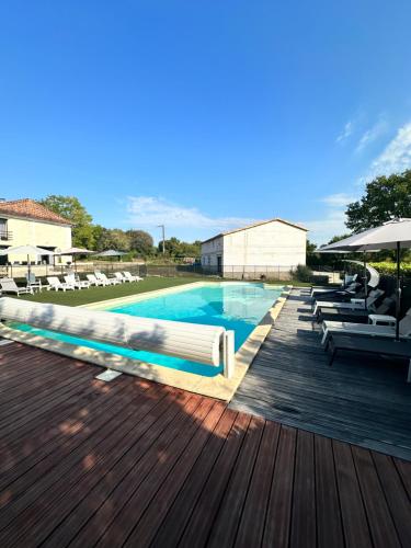 une piscine avec des chaises et une terrasse en bois dans l'établissement Domaine de la Roche Chabrelle, à Saint-Just