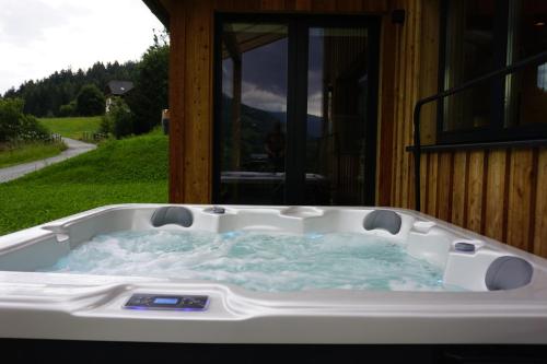 a hot tub in front of a house at Alpenchalét Alpakablick in Sankt Lorenzen ob Murau