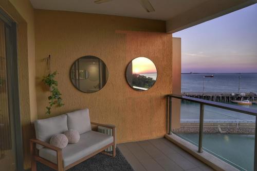 Un balcón con una silla y vistas al océano. en Penthouse-level Waterfront Apartment, en Darwin