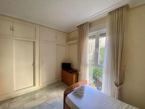 - une chambre avec un lit et une grande fenêtre dans l'établissement RentalSevilla en el barrio de Nervión, à Séville