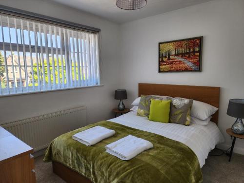 1 dormitorio con 1 cama con 2 toallas en Kennedy Villa - 5 Bed House with Hot Tub, en Bicester