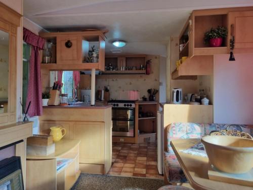 a kitchen with wooden cabinets and a table in a caravan at Domek holenderski - drewniany w centrum Kaszub in Szklana Huta