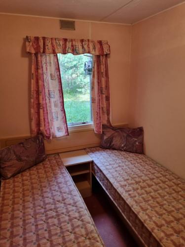 a small room with two beds and a window at Domek holenderski - drewniany w centrum Kaszub in Szklana Huta