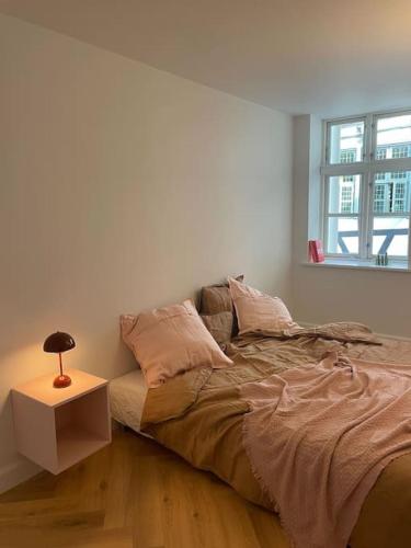 a bedroom with a bed and a lamp on a table at Nyrenoveret charmerende lejlighed i Odense C! in Odense