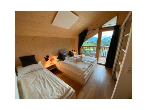 a bedroom with two beds and a balcony at Alpenchalét Alpakablick in Sankt Lorenzen ob Murau