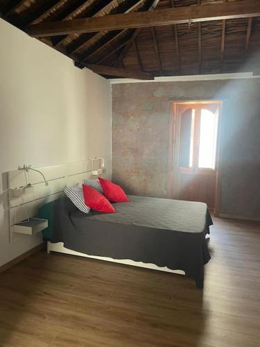 a bedroom with a bed with red pillows and a window at Apartamento Mirador del Almendro in Tejeda