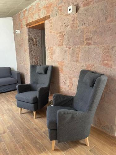 duas cadeiras num quarto com uma parede de tijolos em Apartamento Mirador del Almendro em Tejeda