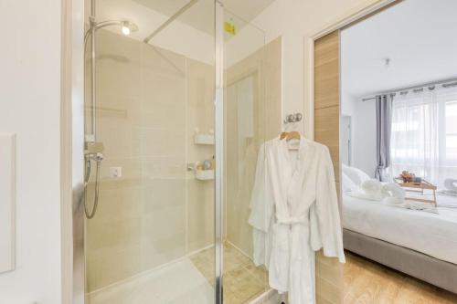 a bathroom with a shower and a robe on a rack at L'élégant T2 proche de Versailles et de Paris in Guyancourt