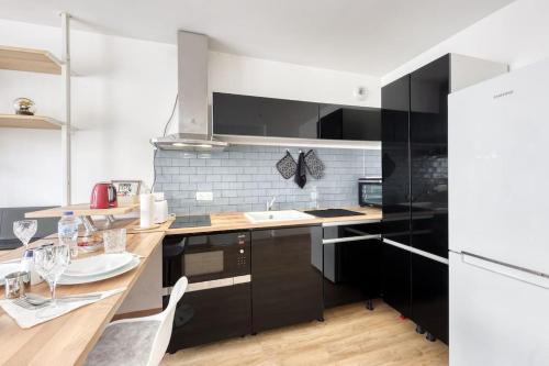 une cuisine avec des armoires noires et une table à manger dans l'établissement L'élégant T2 proche de Versailles et de Paris, à Guyancourt