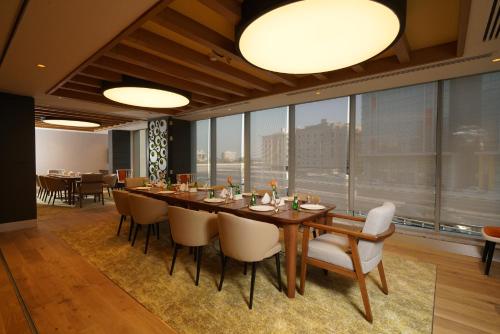 a dining room with a long table and chairs at Ramada Encore Al Khobar Corniche in Al Khobar