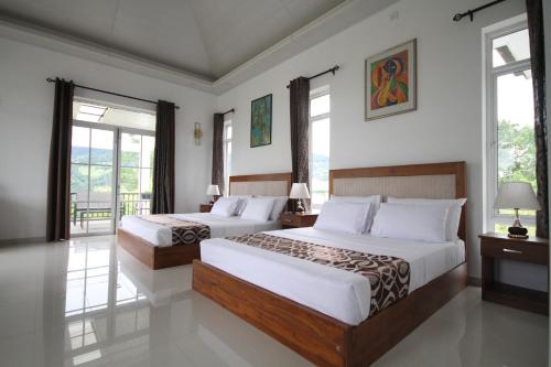 2 camas en una habitación de hotel con ventanas en The Grove, en Kandy