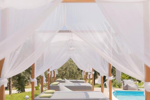 a row of beds under a canopy next to a pool at Skiathos Avaton Garden, Philian Hotels and Resorts in Skiathos