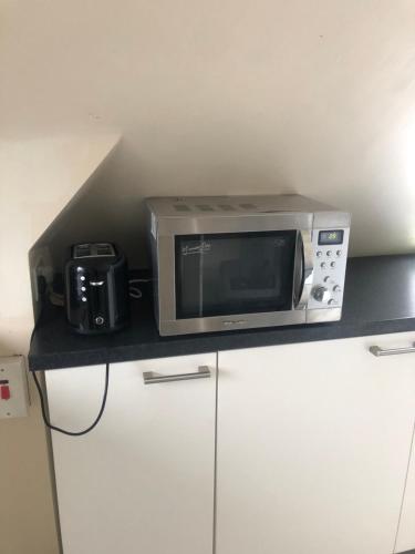 a microwave sitting on top of a counter with a camera at Room with shared kitchen in Mill Hill