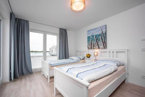 2 łóżka w białej sypialni z oknem w obiekcie Villa SeeZeit w mieście Kappeln