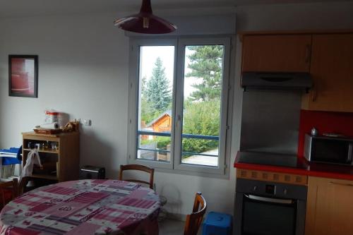 une cuisine avec une table et une grande fenêtre dans l'établissement Vercors Source, à Villard-de-Lans
