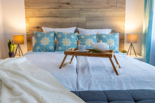 a bed with blue pillows and a wooden head board at Design Apartment-bis 4 Pers-Vollwertige Küche-Parkplatz-WiFi-Garten-Terrasse in Schiffweiler