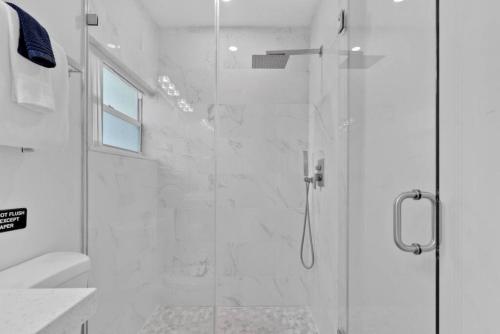 Modern Fort Lauderdale Pool Home في فورت لاودردال: حمام أبيض مع دش مع باب زجاجي