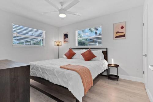 Modern Fort Lauderdale Pool Home في فورت لاودردال: غرفة نوم بيضاء بسرير كبير ونوافذ