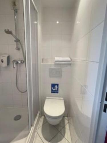 a white bathroom with a toilet and a shower at Premiere Classe Rungis - Orly in Rungis