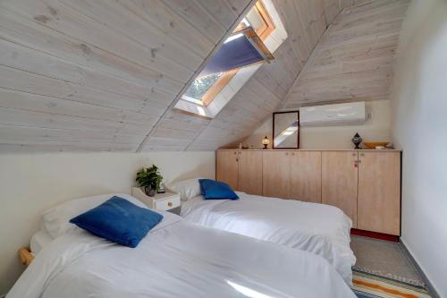 2 Betten in einem Schlafzimmer im Dachgeschoss mit Fenster in der Unterkunft Amanda's place Central Modern spacious family APT in Zichron Ja’akow