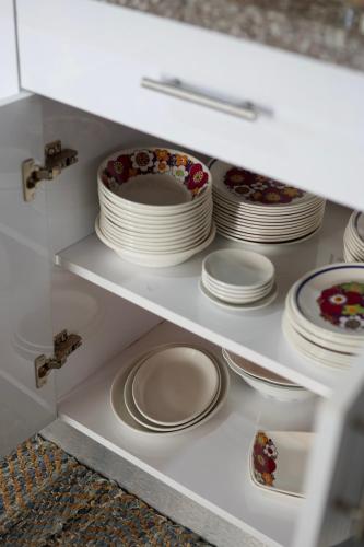 a white cabinet with plates and bowls on it at Amanda's place Central Modern spacious family APT in Zikhron Ya‘aqov