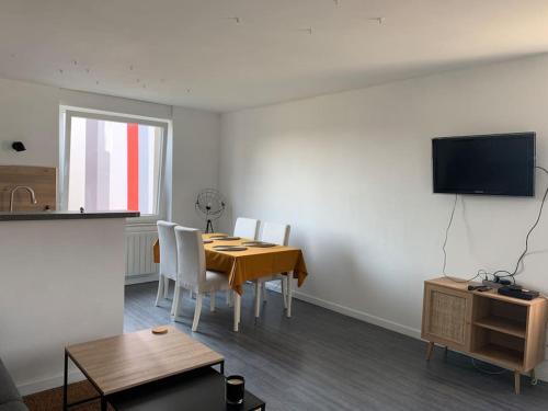 une salle à manger avec une table, des chaises et une télévision dans l'établissement Le cocon de la Sarre, à Sarreguemines