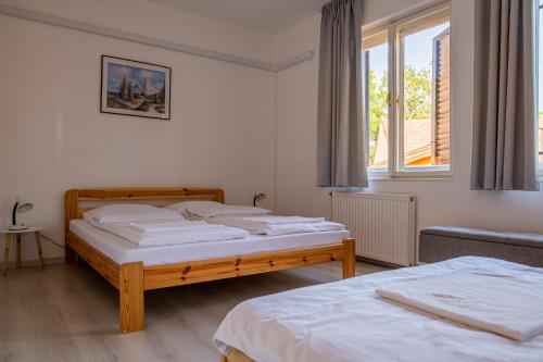 1 dormitorio con 2 camas y ventana en Barát Vendégház - Cosy Guesthouse - Teljes ház privát udvarral - 4 szoba, 2 fürdő, en Szeged
