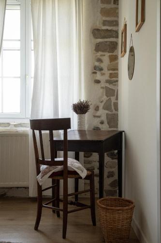 a wooden table and chair in a room with a window at Ferme Sarthou in Lucq-de-Béarn