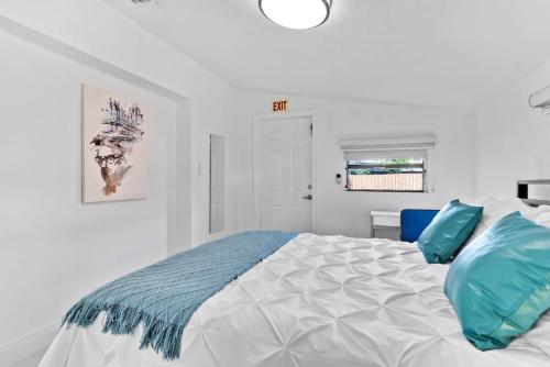 biała sypialnia z łóżkiem z niebieskimi poduszkami w obiekcie 3Bed Glamour Iconic Hollywood Pool Home w mieście Hollywood