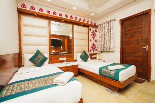ein Hotelzimmer mit 2 Betten und einem Spiegel in der Unterkunft Hotel Kabir Palace Karol Bagh in Neu-Delhi