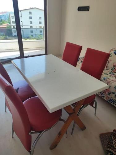 a white table and four red chairs in a room at Студия комфорт Comfort Studio كومفورت ستوديو 112 in Çınarcık