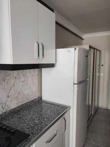 a kitchen with white cabinets and a white refrigerator at Студия комфорт Comfort Studio كومفورت ستوديو 112 in Çınarcık