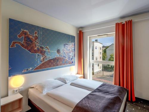 a bedroom with a bed and a large painting on the wall at B&B HOTEL Magdeburg-City in Magdeburg
