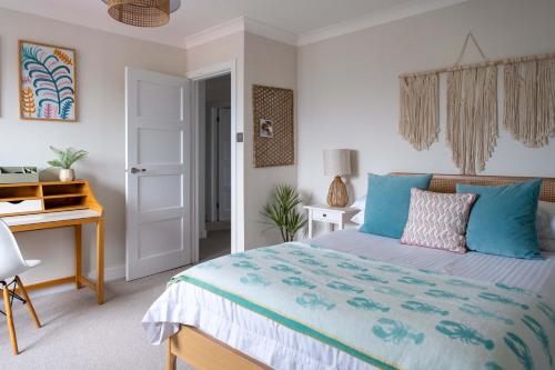 een slaapkamer met een bed met blauwe kussens en een bureau bij Cliff House in Lymington