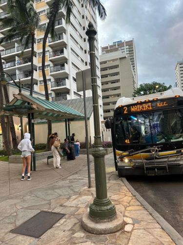 a bus is pulling up to a bus stop at WELLCOME TO LOVELY CONDO 2 BEDS 2 BATHS FREE PARKING IN WAIKIKI BEACH in Honolulu