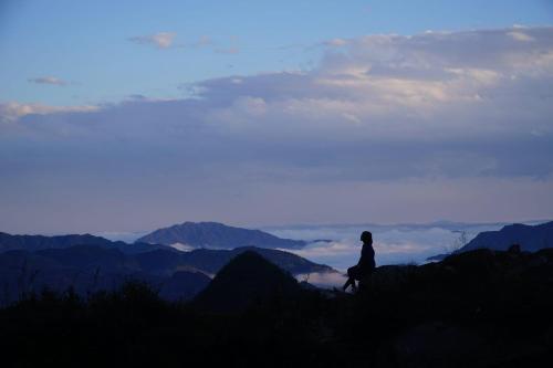a person standing on top of a mountain looking at the view at Cong Fu Hotel in Bắc Hà