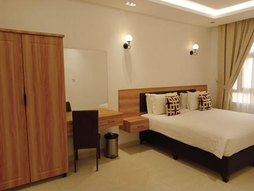 a bedroom with a bed and a desk and a table at Nizwa Hotel Apartments in Nizwa