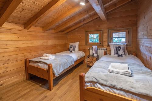 a bedroom with two beds in a log cabin at Chalet Luxe Les Orchis Alpe d'Huez in LʼHuez