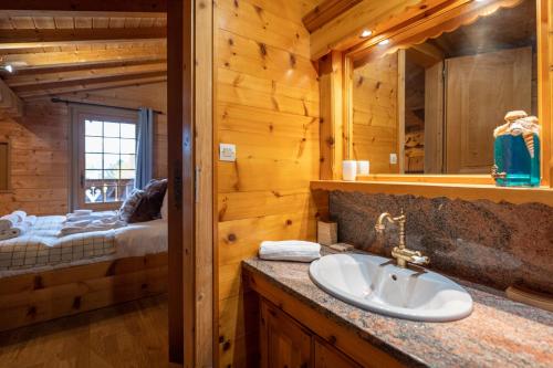 a bathroom with a sink in a log cabin at Chalet Luxe Les Orchis Alpe d'Huez in LʼHuez