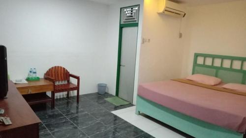 een slaapkamer met een bed, een tafel en een stoel bij Hotel sahabat baru in Singkawang