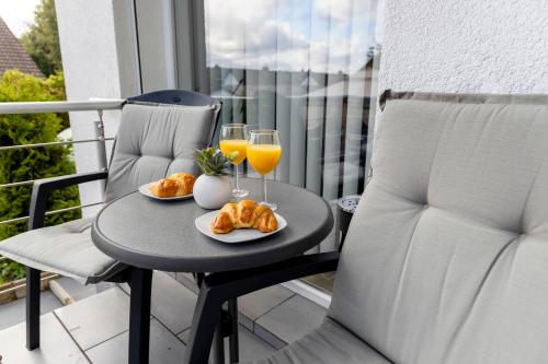 a table with two glasses of orange juice and croissants at Design Apartment-bis 4 Pers-Vollwertige Küche-Parkplatz-WiFi-Garten-Terrasse in Schiffweiler