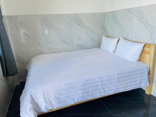 a bed with white sheets and pillows in a room at Ánh Mai Hotel in Bảo Lộc