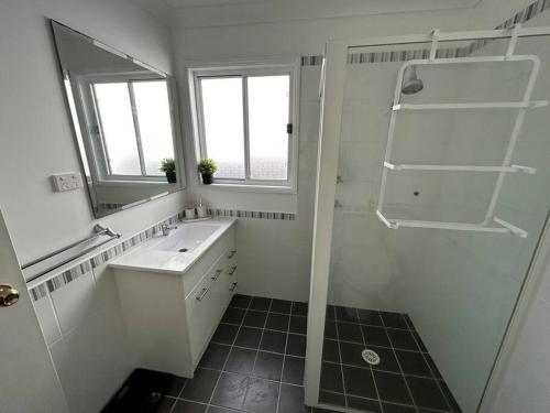 ein weißes Badezimmer mit Waschbecken und Dusche in der Unterkunft Absolutely Lakeside House, quiet and peace in Killarney