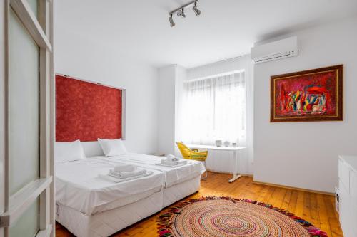 een slaapkamer met een wit bed en een rode muur bij Sofia's Vintage Gem: Spacious 2BD Flat on Solunska in Sofia