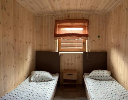 two beds in a small room with a window at Atostogų namelis in Kurėnai