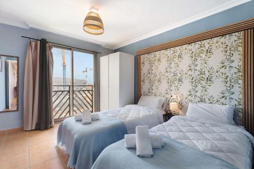 Un dormitorio con dos camas y una gran ventana. en Duplex Tejita Beach, en Granadilla de Abona